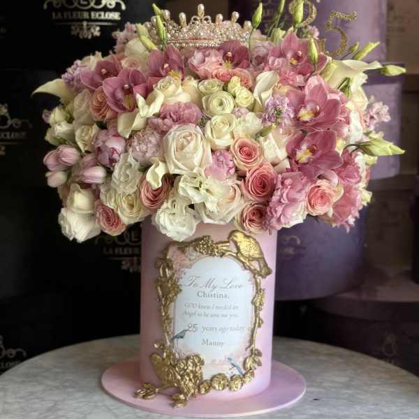 Pink and white floral arrangement in a decorated hatbox with a jeweled topper