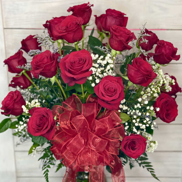 Bouquet of red roses with baby's breath and a red ribbon in a glass vase