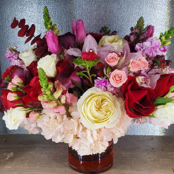 Mixed bouquet of red, pink, and white flowers in a glass vase