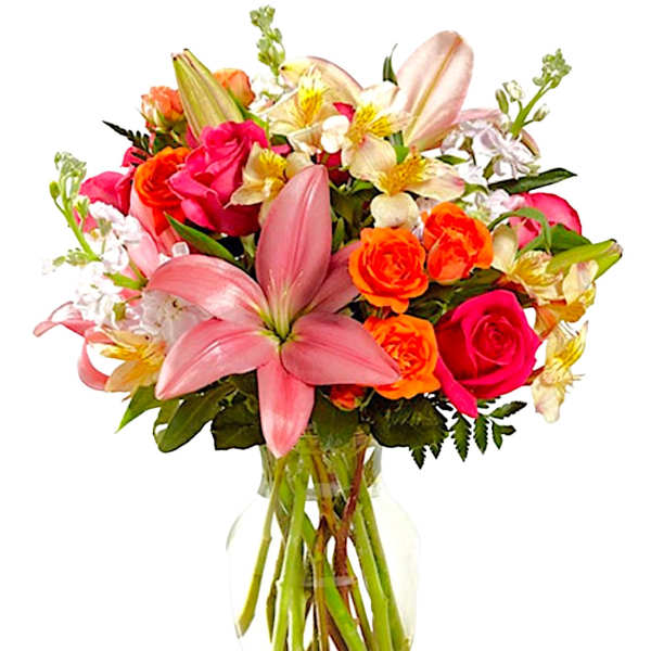 Mixed bouquet of pink lilies, roses, and orange blooms in a glass vase