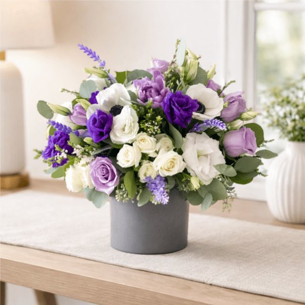 Purple and white floral arrangement in a gray vase