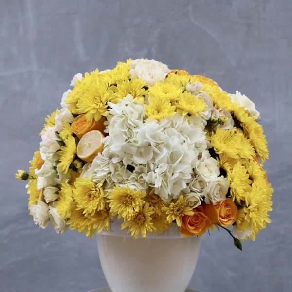 Yellow and white floral arrangement in a white vase
