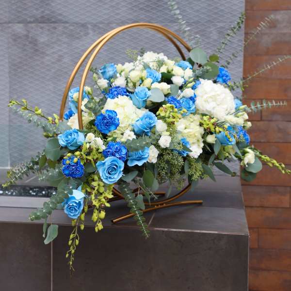Blue and white floral arrangement in a gold hoop stand