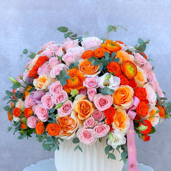 Large bouquet of pink and orange roses in a white vase