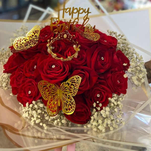 Bouquet of red roses with gold butterfly decorations and a birthday topper