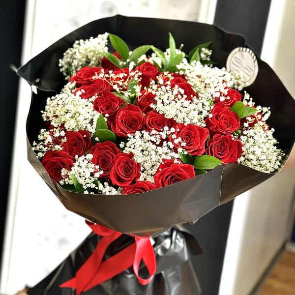 Bouquet of red roses with white baby's breath wrapped in black paper