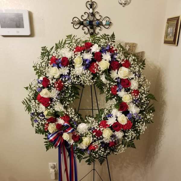 Large patriotic funeral wreath with red, white, and blue flowers on a stand