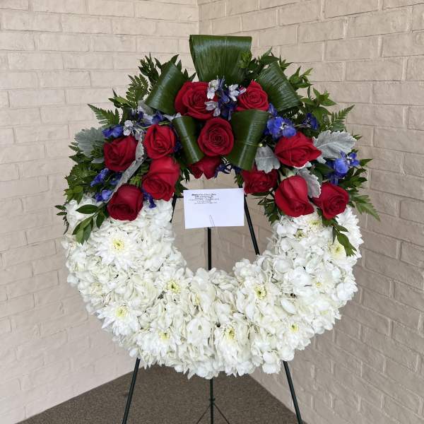Circular floral wreath with red roses and white chrysanthemums on a stand