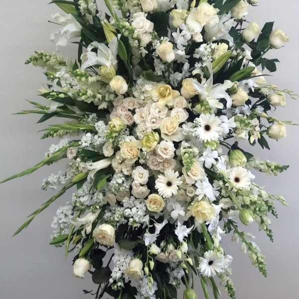 Large white funeral spray with roses, lilies, and gerbera daisies