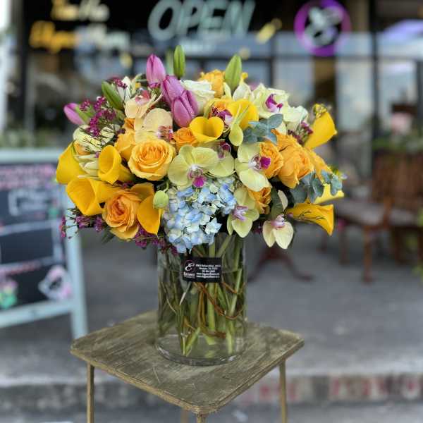 Bright mixed bouquet in a clear glass vase on a small table