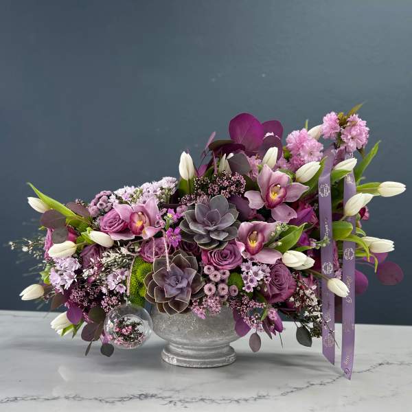 Purple floral arrangement with white tulips in a silver vase