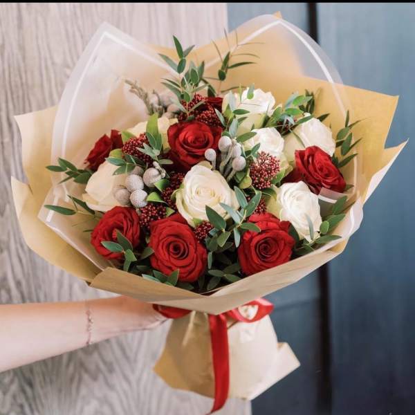 Bouquet of red and white roses wrapped in tan paper with a red ribbon