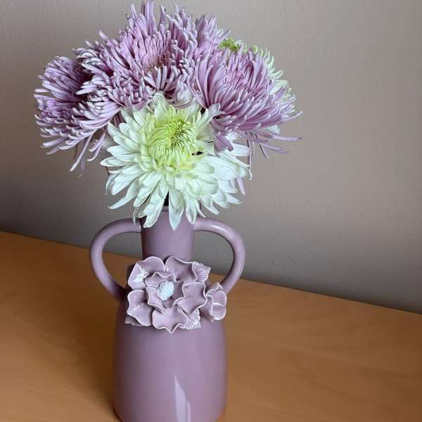 Lavender and white chrysanthemums in a pink vase with handles