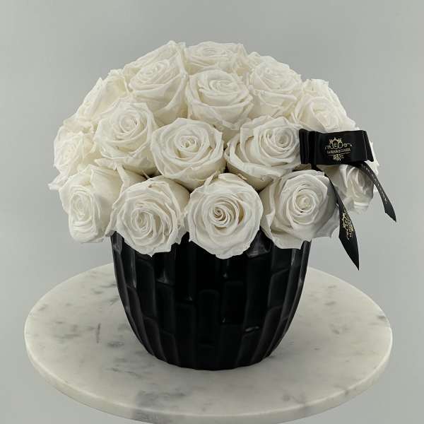 White rose bouquet in a black vase with a ribbon
