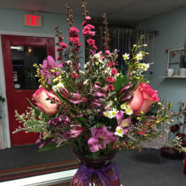 Tall mixed bouquet in a glass vase with pink and purple flowers