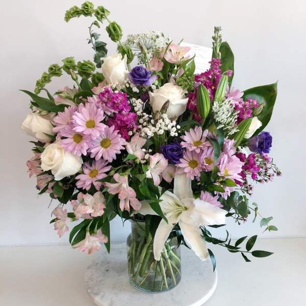 Mixed bouquet of pink, white, and purple flowers in a glass vase