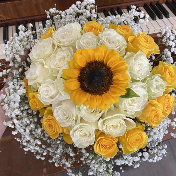 Bouquet of yellow and white roses with a sunflower center