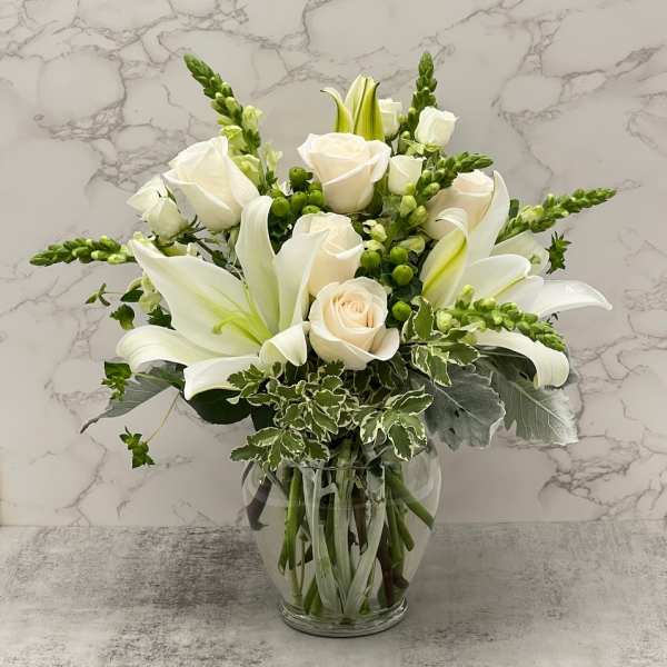 White roses and lilies arranged in a clear glass vase