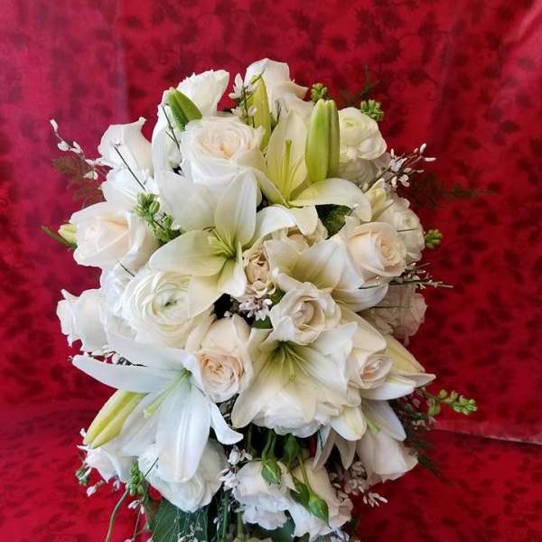 White bouquet of lilies and roses against a red background