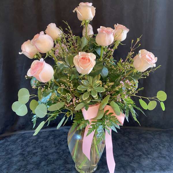 Pink roses in a glass vase with a pink ribbon