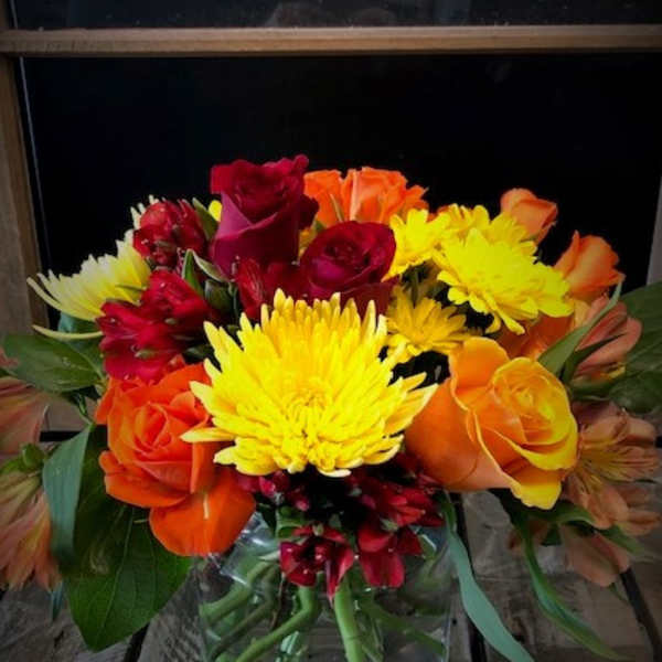 Mixed bouquet of roses, chrysanthemums, and alstroemeria in a glass vase