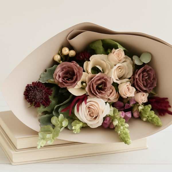 Bouquet of blush and burgundy roses wrapped in beige paper