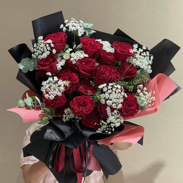 Bouquet of red roses with white filler flowers and black-and-pink wrapping