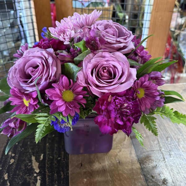 Purple rose and daisy bouquet in a square vase