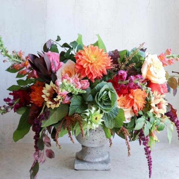 Large mixed flower arrangement in a stone pedestal vase