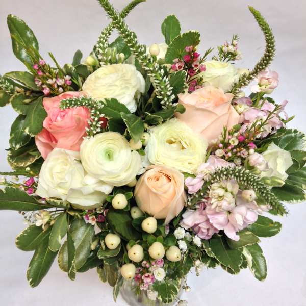 Mixed bouquet of pale roses and white blooms in a glass vase
