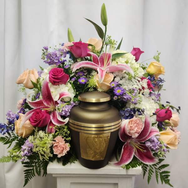 Floral arrangement surrounding a bronze urn with pink lilies and roses