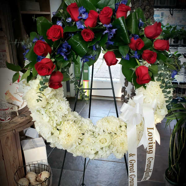 Large standing wreath of red roses and white flowers with a ribbon