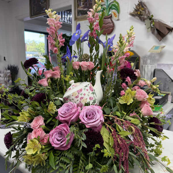 Mixed floral arrangement with roses, snapdragons, and a floral teapot centerpiece