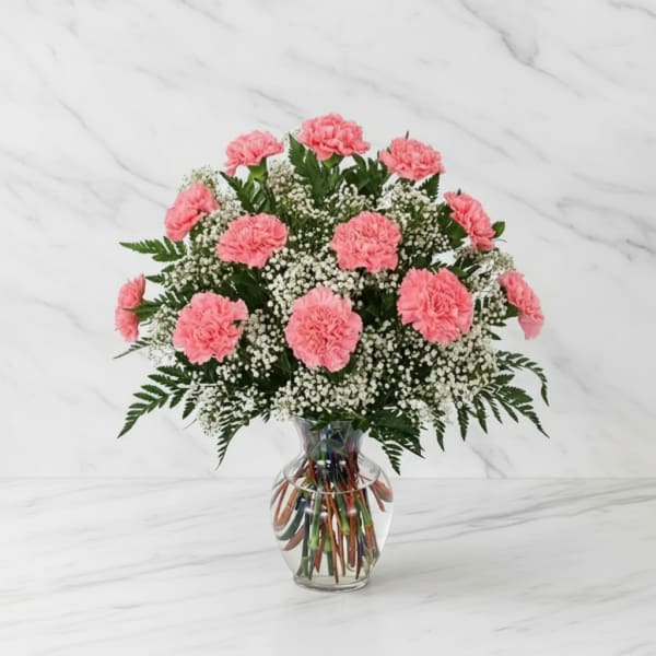 Pink carnations in a clear glass vase with white filler flowers