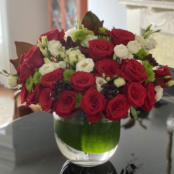 Red and white roses in a clear glass vase with green accents