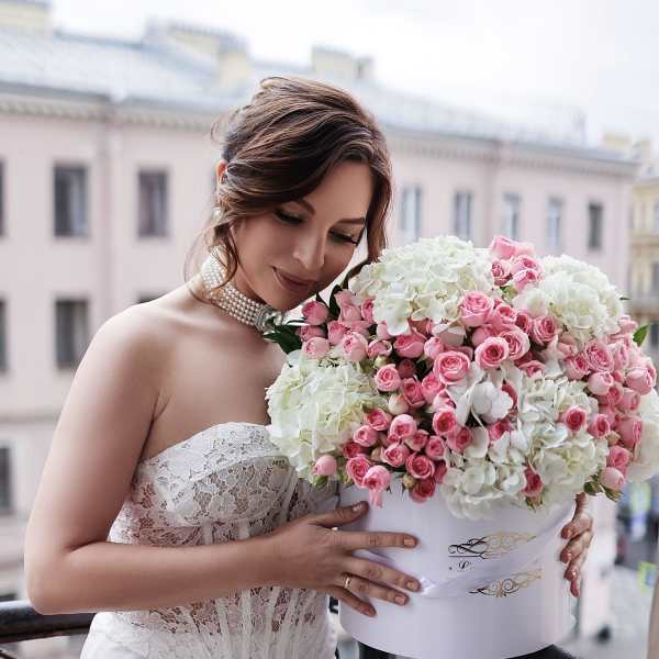 Bride holding a large pink and white rose bouquet in a white box