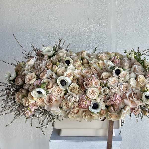 Large pastel bouquet of roses and white anemones in a rectangular vase