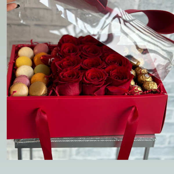 Red roses in a gift box with macarons and chocolates