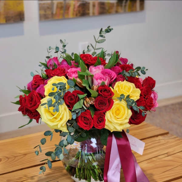 Bouquet of red and yellow roses in a glass vase with ribbon
