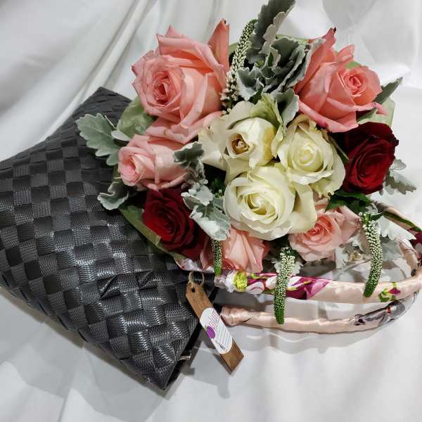 Bouquet of pink, white, and red roses with silver foliage in a black wrap