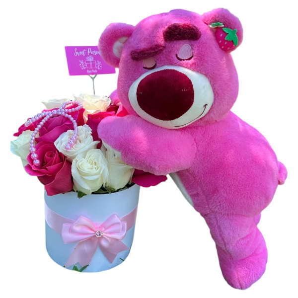 Pink teddy bear leaning on a box of roses