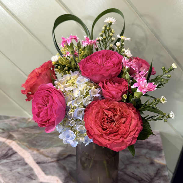Pink roses and hydrangea in a dark glass vase