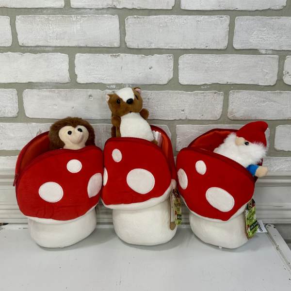 Three plush holiday gnomes in red mushroom-shaped pouches