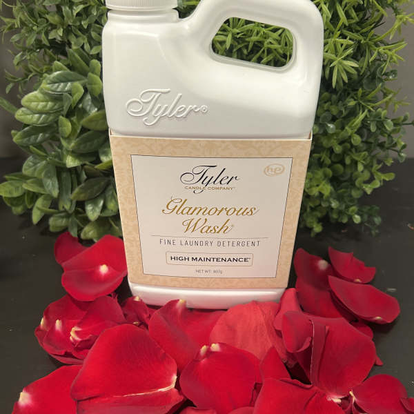 Laundry detergent bottle surrounded by red rose petals and greenery