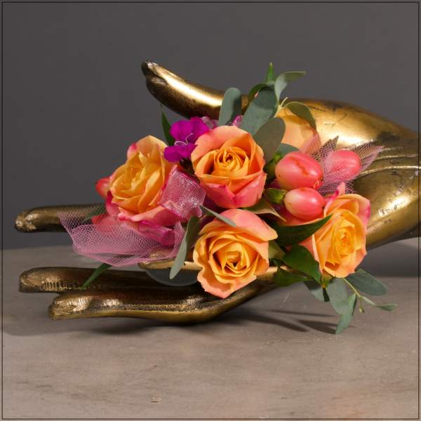 Orange and pink rose bouquet with ribbon in a gold hand sculpture