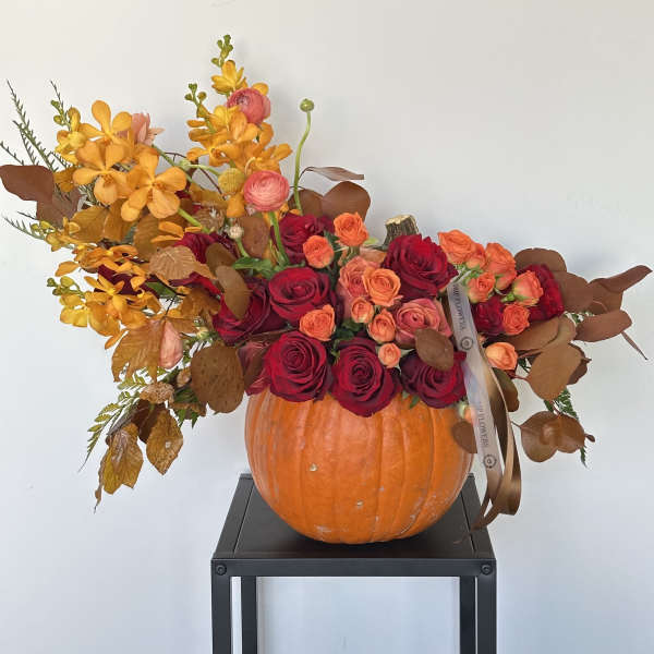 Pumpkin arrangement with red roses and orange flowers