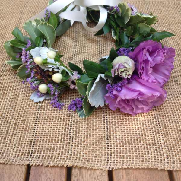 Floral wreath with purple blooms and white ribbon on burlap