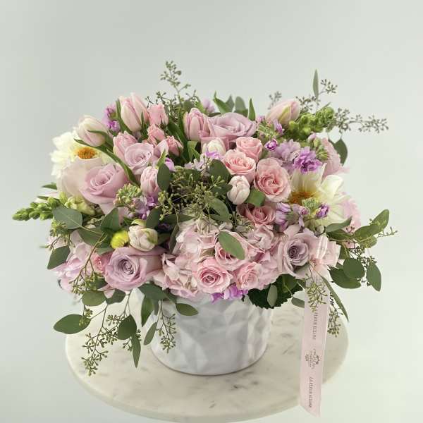 Pink and lavender rose bouquet in a white vase