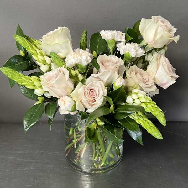 Blush roses and white carnations in a clear glass vase