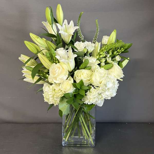 White lilies and roses arranged in a clear glass vase